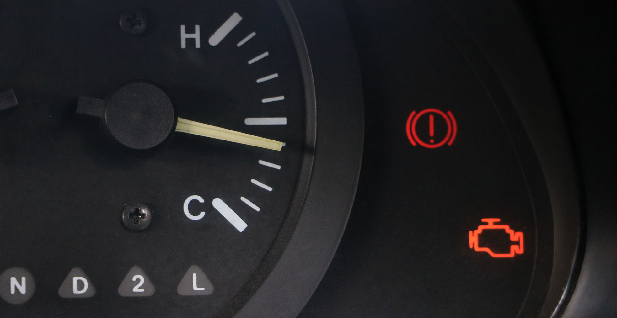 Car dashboard showing illuminated warning lights, including the check engine light and brake warning indicator.