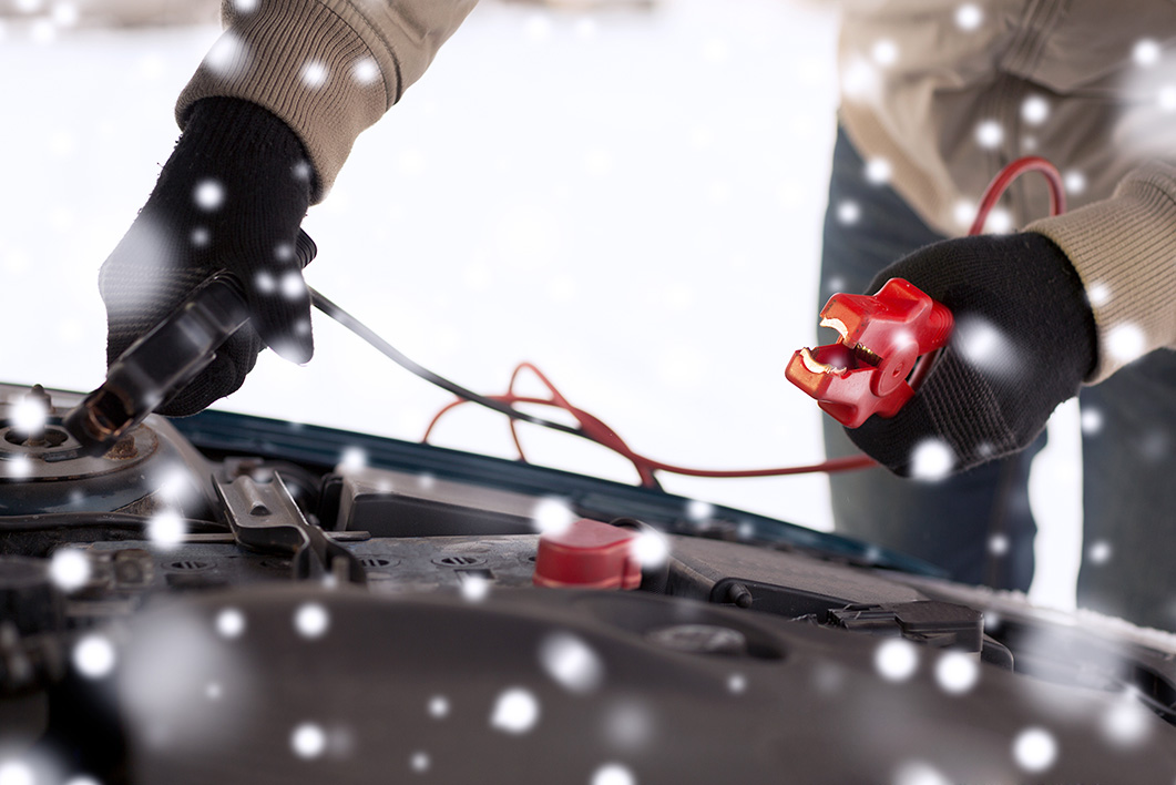 Jump-starting a car battery with jumper cables in cold weather.